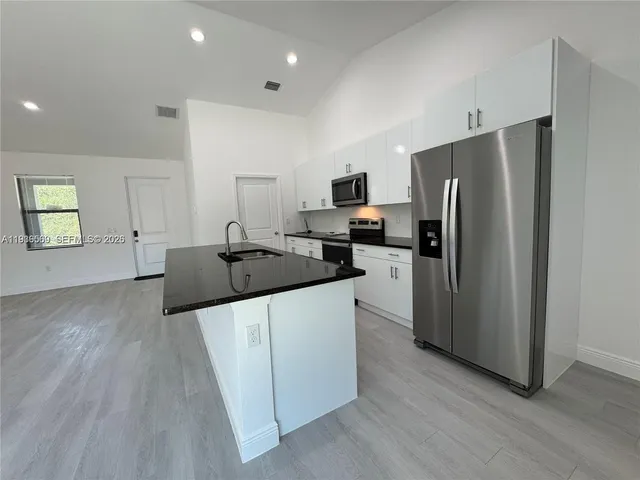 a kitchen with granite countertop a refrigerator and a stove top oven