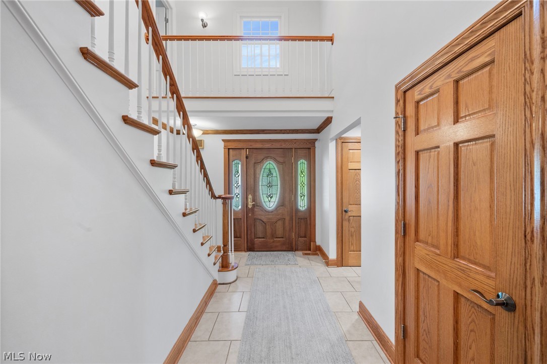 3871 Greentree Road Stow, OH 44224 - Photo 39 of 50 Two-story foyer featuring a grand staircase with white spindles and wood handrails, a wood-paneled entry door with frosted glass inserts, and ceramic tile flooring
