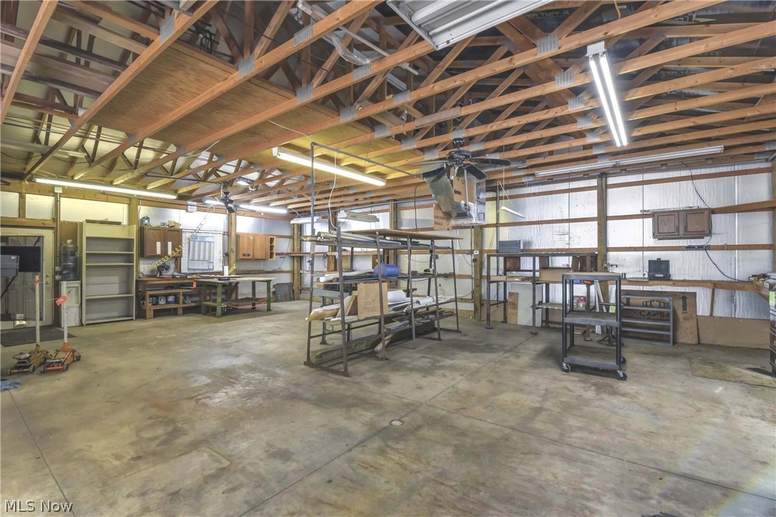 301 Crosse Road Amherst, OH 44001 - Photo 40 of 49 Spacious insulated workshop featuring a furnace for heat, exposed wood beams, built-in shelving, overhead lighting, ceiling fan, and concrete flooring.