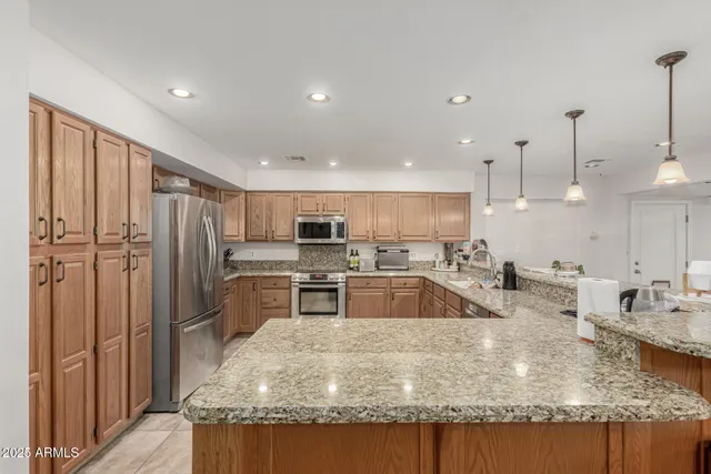a kitchen with stainless steel appliances granite countertop a sink a stove and a refrigerator
