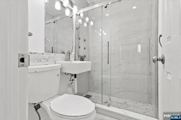 a bathroom with a granite countertop sink a toilet a mirror and shower