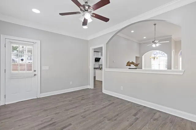 a view of an empty room with wooden floor and a window