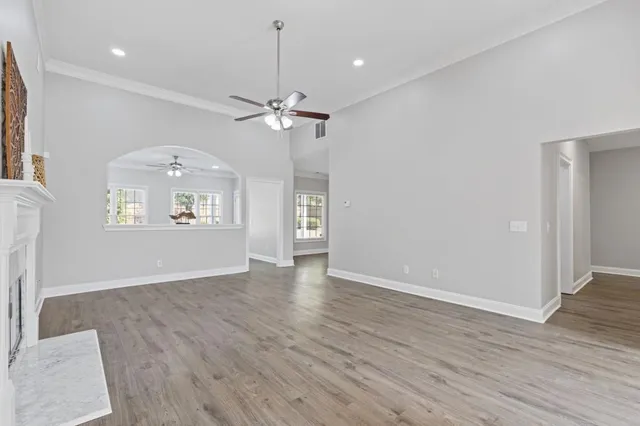 an empty room with wooden floor fireplace and fan