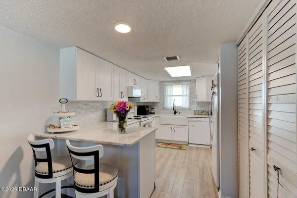 a kitchen with white cabinets and chairs