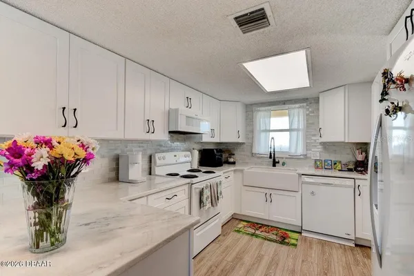 a kitchen with granite countertop a sink cabinets stainless steel appliances and a window