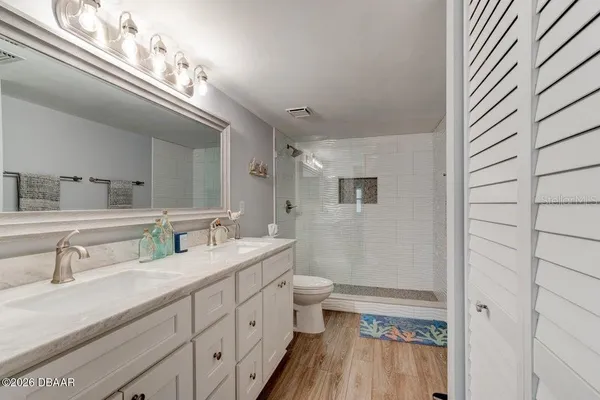 a spacious bathroom with a double vanity sink a toilet and a mirror