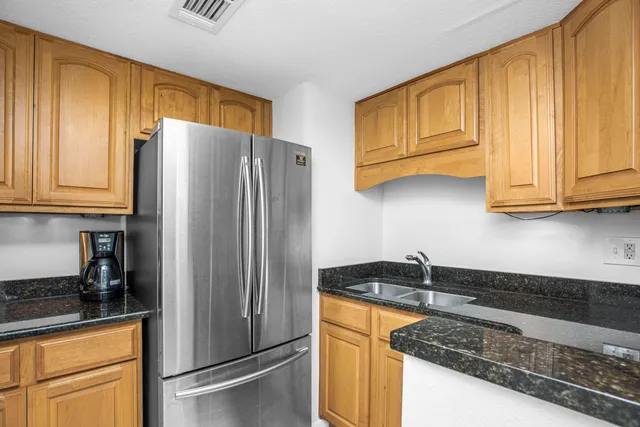 a kitchen with granite countertop wooden cabinets and a refrigerator