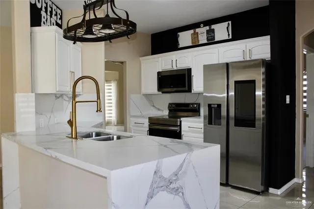 a kitchen with stainless steel appliances a sink a microwave a refrigerator and cabinets