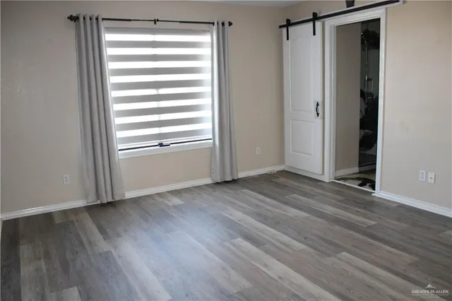 a view of empty room with wooden floor and window