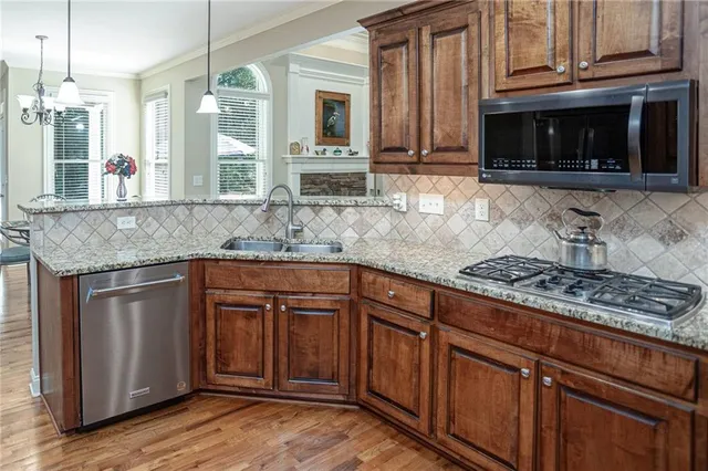 a kitchen with stainless steel appliances granite countertop a stove a sink and a microwave