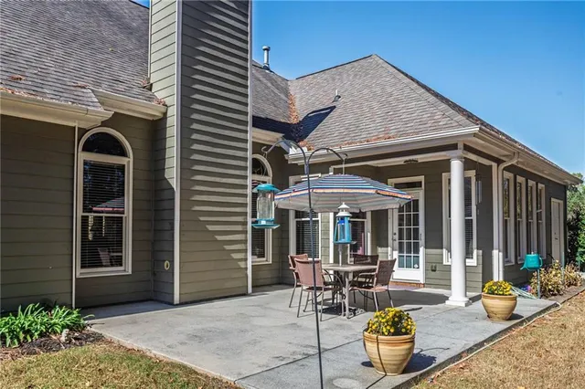 a patio with a table and chairs and potted plants