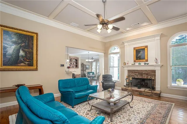 a living room with couches a fireplace and a dining table with wooden floor