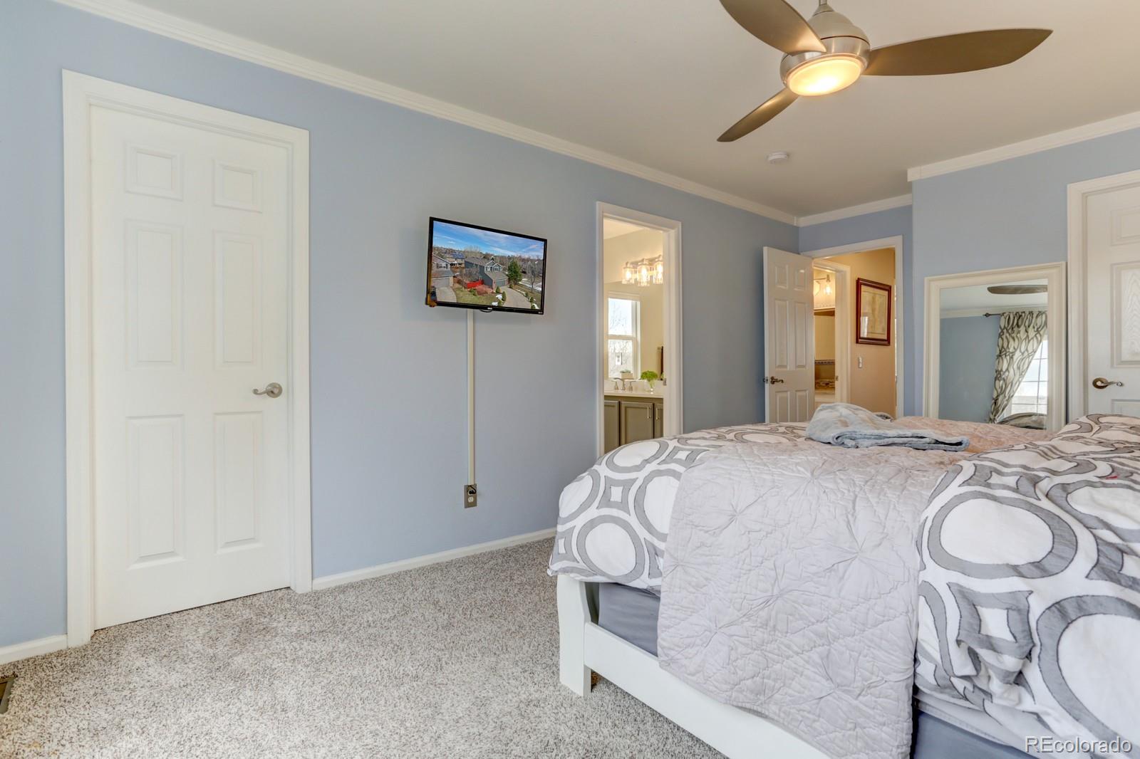 801 Riddlewood Lane Highlands Ranch, CO 80129 - Photo 19 of 40 a spacious bedroom with a bed and a chandelier