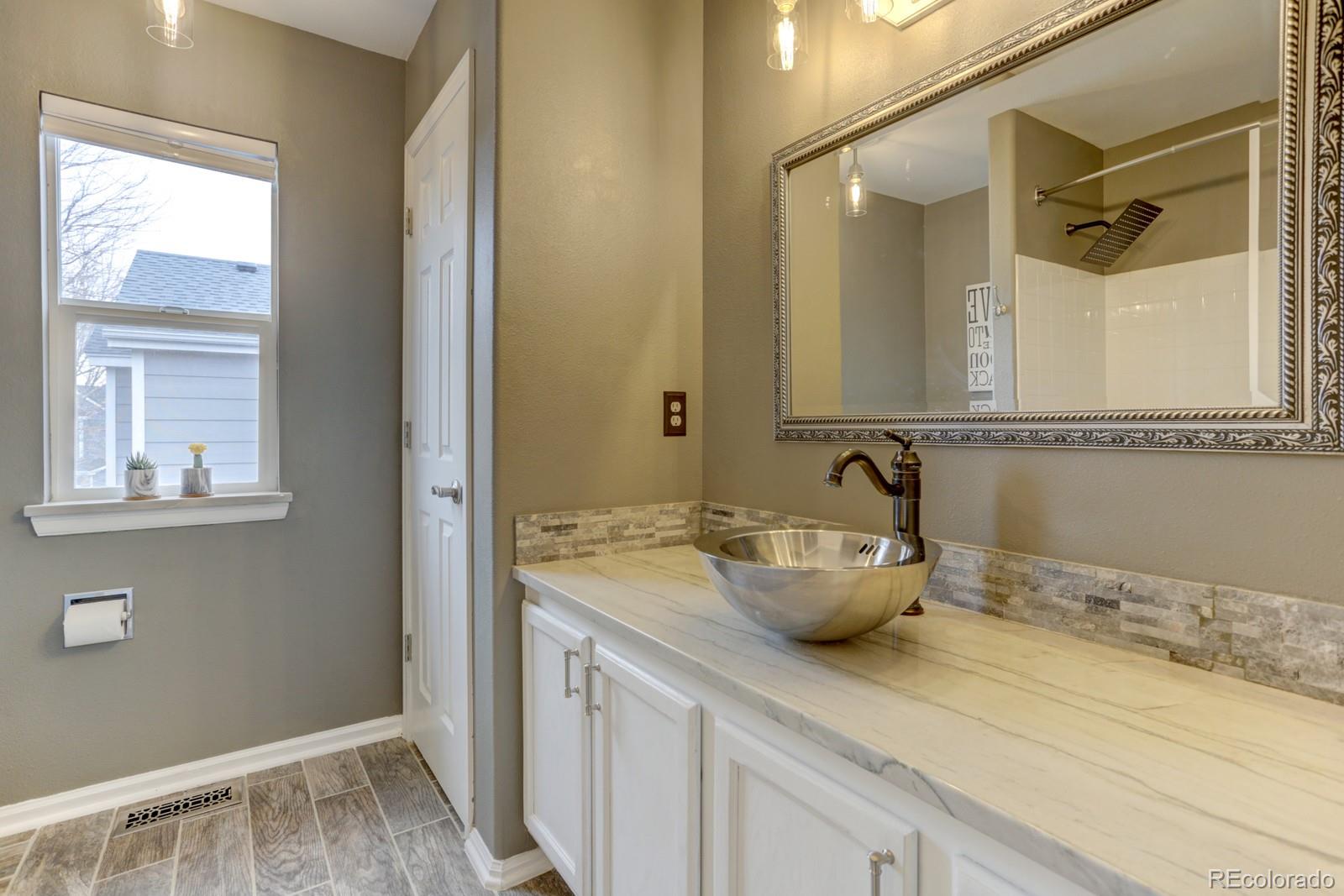 801 Riddlewood Lane Highlands Ranch, CO 80129 - Photo 24 of 40 a bathroom with a granite countertop sink mirror and window