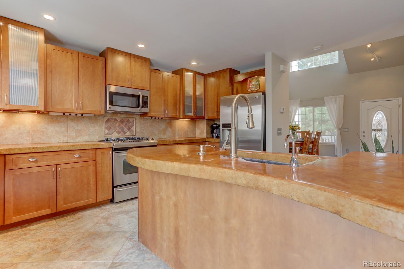 801 Riddlewood Lane Highlands Ranch, CO 80129 - Photo 7 of 40 a kitchen with stainless steel appliances granite countertop a sink a stove top oven a counter space and cabinets