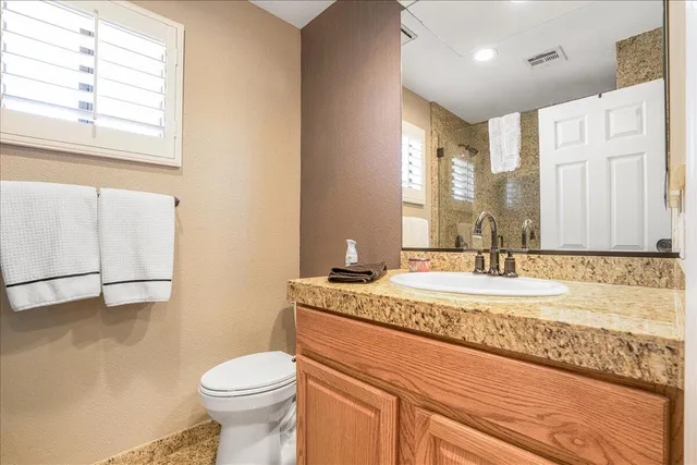 a bathroom with a granite countertop sink mirror vanity and toilet