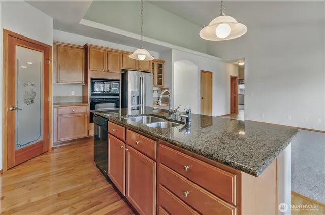 a kitchen with stainless steel appliances granite countertop a sink and a refrigerator