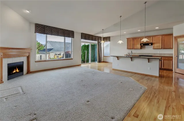 a open kitchen with stainless steel appliances granite countertop a stove top oven a sink dishwasher a dining table and chairs with wooden floor