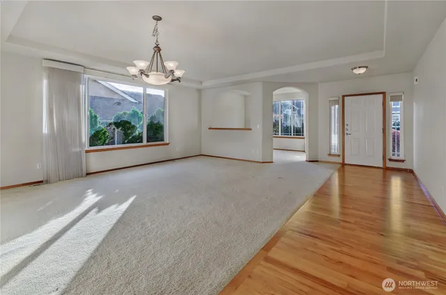 a view of a livingroom with wooden floor a ceiling fan and windows