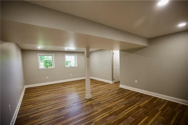 a view of a hallway with wooden floor and a bathroom