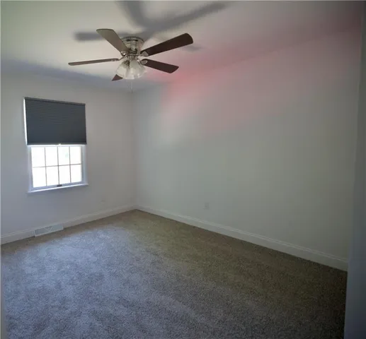 an empty room with a ceiling fan and window