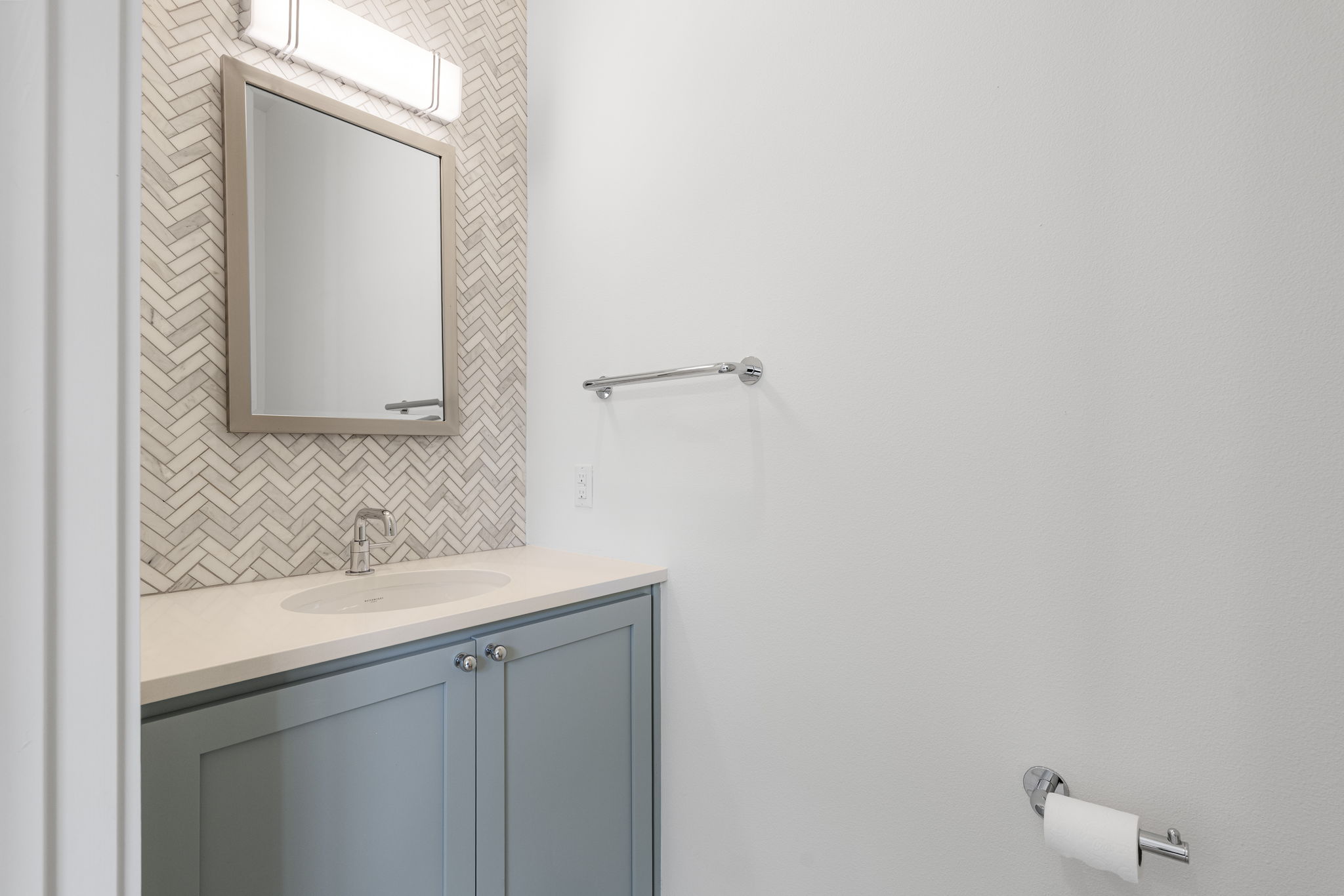 2520 Sutherland Street Austin, TX 78746 - Photo 22 of 26 A well-appointed first floor guest bathroom with a wall of herringbone mosaic Carrera Mable, and Waterworks luxury fixtures.