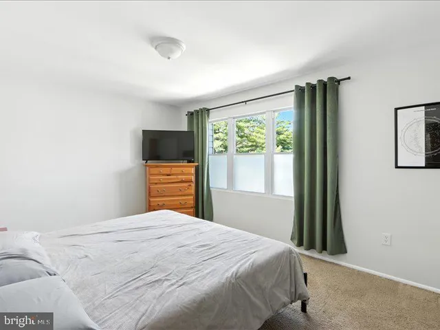 a bedroom with a bed and a flat tv screen on a dresser