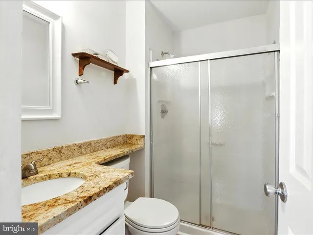 a bathroom with a granite countertop sink toilet and shower