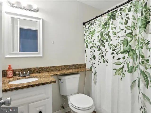 a bathroom with a granite countertop sink and a toilet