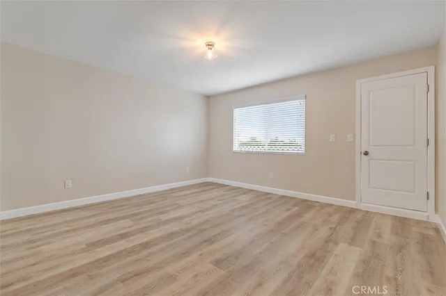 an empty room with wooden floor and mirror