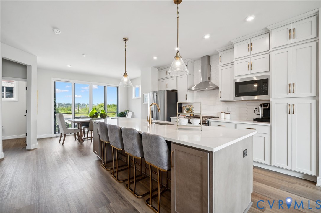 16116 Esteem Way Midlothian, VA 23113 - Photo 9 of 42 a kitchen with stainless steel appliances kitchen island granite countertop a stove a refrigerator a sink a dining table and chairs with wooden floor