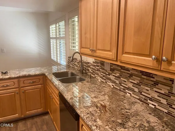 a kitchen with granite countertop a sink a stove and cabinets