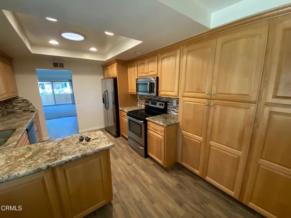 a kitchen with granite countertop a refrigerator a sink dishwasher and wooden cabinets