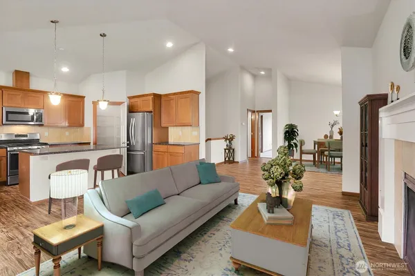 a living room with furniture kitchen view and a wooden floor