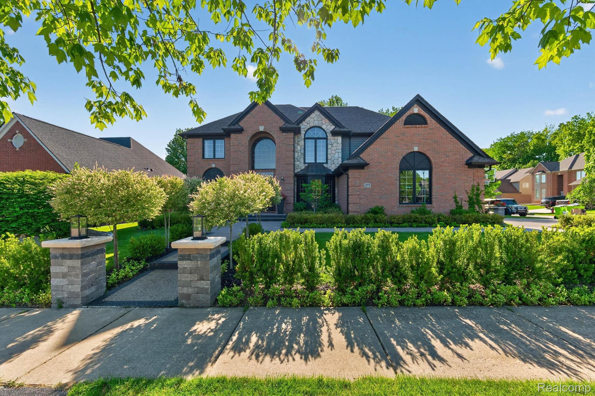 371 Lone Pine Circle Rochester, MI 48307 - Photo 1 of 59 Brick and stone facade residence featuring arched windows, a prominent gable, and a dark shingle roof
