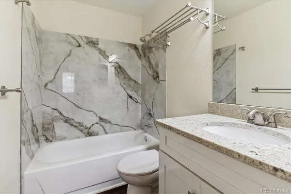 a bathroom with a granite countertop sink toilet and shower