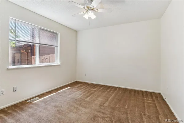 an empty room with a window and a fan