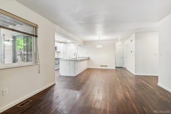 a view of a kitchen with wooden floor and a window