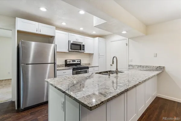 a kitchen with kitchen island granite countertop a sink refrigerator and microwave