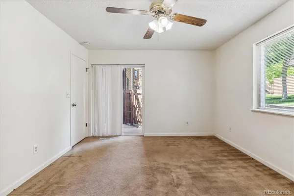 an empty room with windows and fan