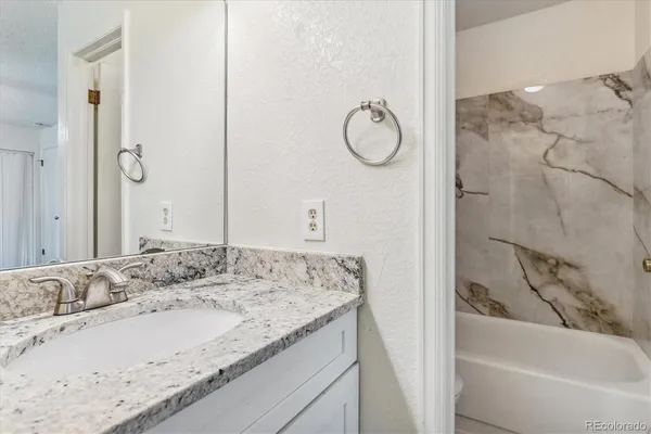 a bathroom with a granite countertop sink mirror and a bathtub