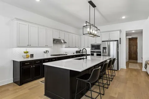 a kitchen with stainless steel appliances a table chairs and a refrigerator