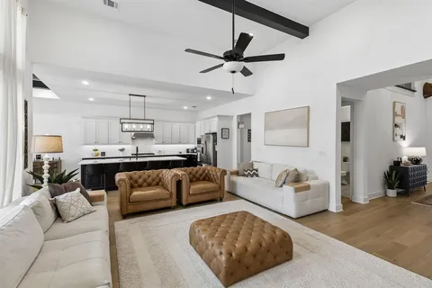 a living room with furniture kitchen view and a chandelier