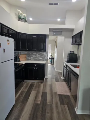 a large kitchen with stainless steel appliances kitchen island granite countertop a stove a refrigerator a sink a dining table and chairs with wooden floor