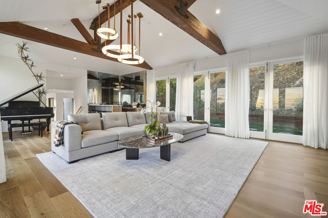 3140 Sweetwater Mesa Road Malibu, CA 90265 - Photo 11 of 71 a living room with furniture a large window and a chandelier