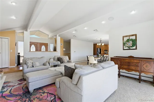 a kitchen with stainless steel appliances granite countertop a refrigerator a sink dishwasher a stove and a dining table with wooden floor