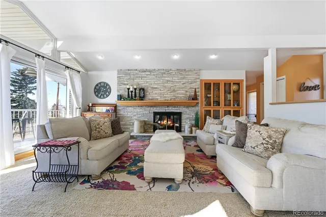 a living room with furniture a fireplace and a floor to ceiling window
