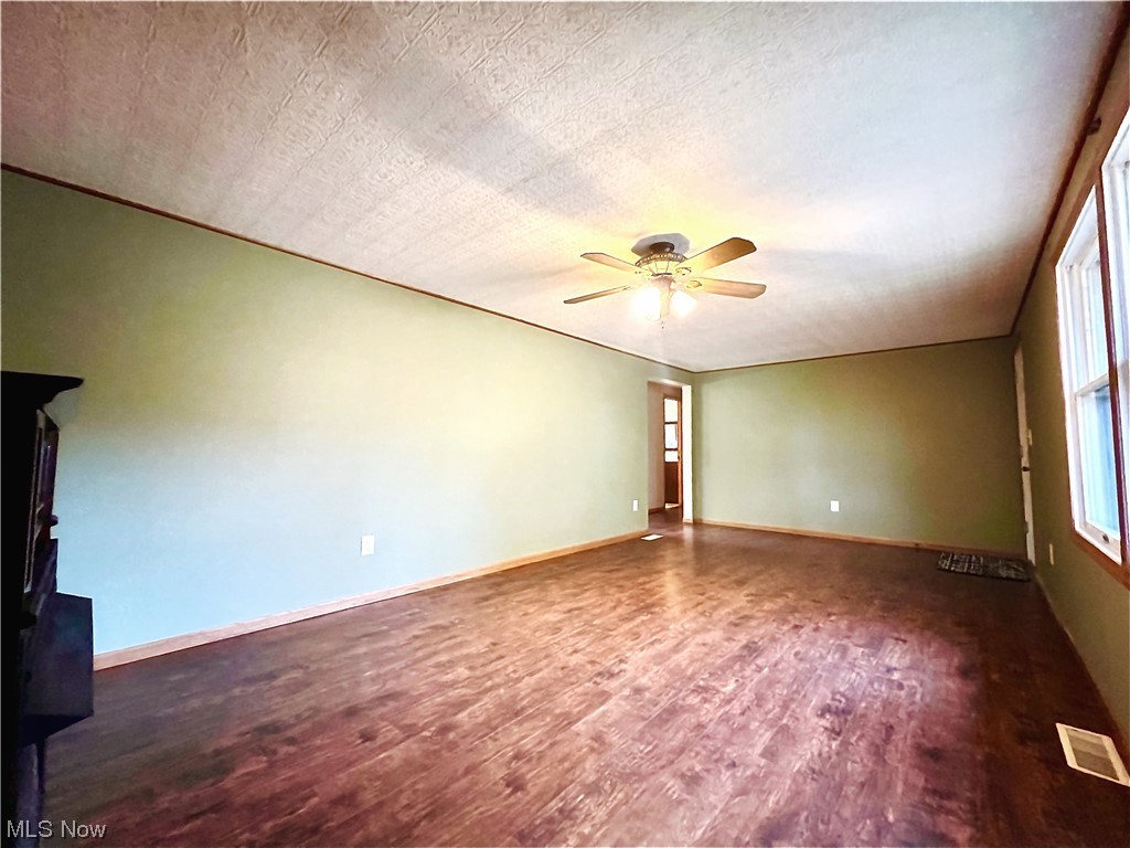 3122 Bedrock Road Northwest Dellroy, OH 44620 - Photo 10 of 23 Empty room featuring ceiling fan, dark hardwood / wood-style flooring, and a textured ceiling