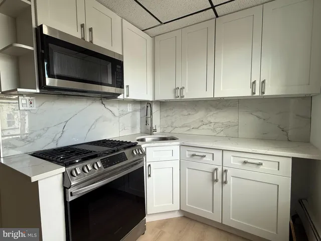 a kitchen with granite countertop white cabinets and stainless steel appliances