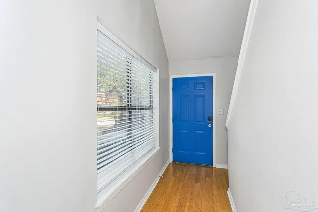 a view of a hallway with wooden floor and a bathroom